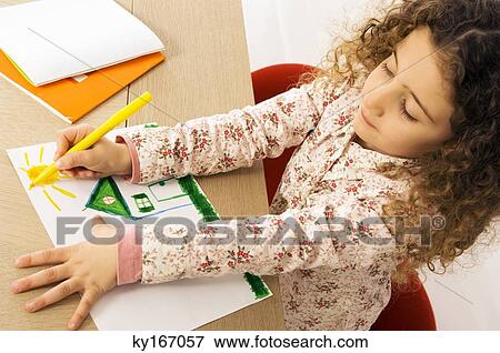 Stock Photo - High angle view of a girl coloring on a sheet of paper. Fotosearch