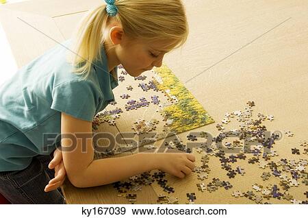 Stock Photo - High angle view of a girl playing a jigsaw puzzle. Fotosearch
