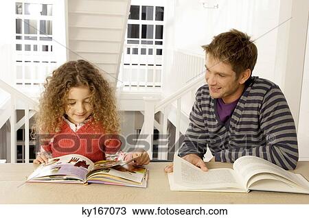 Mid adult man sitting with his daughter and reading books View Large Photo Image Stock Image - Mid adult man sitting with his daughter and reading books. Fotosearch