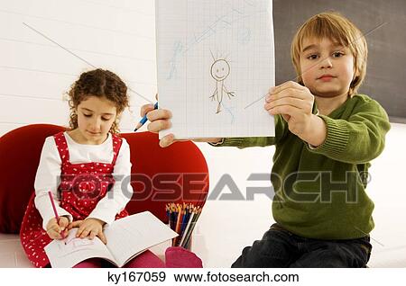 Portrait of a boy showing a drawing with his sister sitting in the background View Large Photo Image Stock Photo - Portrait of a boy showing a drawing with his sister sitting in the background. Fotosearch