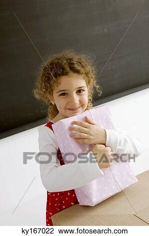 Stock Image - Portrait of a girl holding a gift and smiling. Fotosearch