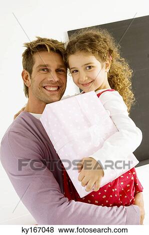 Portrait of a mid adult man carrying his daughter with a gift View Large Photo Image Stock Photo - Portrait of a mid adult man carrying his daughter with a gift. Fotosearch