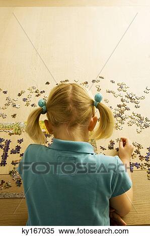 Rear view of a girl playing a jigsaw puzzle View Large Photo Image Stock Photography - Rear view of a girl playing a jigsaw puzzle. Fotosearch