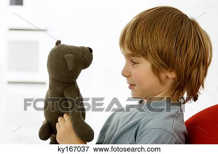 Side profile of a boy holding a teddy bear View Large Photo Image Stock Photo - Side profile of a boy holding a teddy bear. Fotosearch
