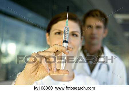 Close-up of a female doctor holding a syringe View Large Photo Image Stock Image - Close-up of a female doctor holding a syringe. Fotosearch
