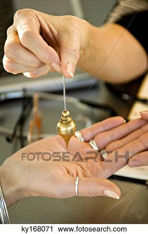 Close-up of a woman's hand holding a dowsing pendulum over a woman's palm View Large Photo Image Stock Image - Close-up of a woman's hand holding a dowsing pendulum over a woman's palm. Fotosearch
