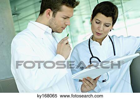 Stock Photography - Close-up of two doctors discussing a medical record. Fotosearch