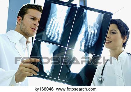 Close-up of two doctors examining an X-Ray report View Large Photo Image Stock Photograph - Close-up of two doctors examining an X-Ray report. Fotosearch
