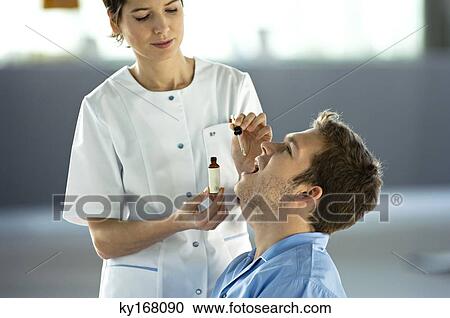 Female doctor giving medicine drops to a male patient View Large Photo Image Stock Image - Female doctor giving medicine drops to a male patient. Fotosearch