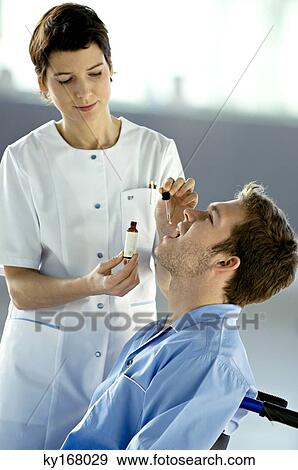 Female doctor giving medicine drops to a male patient View Large Photo Image Stock Photo - Female doctor giving medicine drops to a male patient. Fotosearch