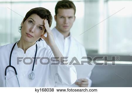 Female doctor looking worried with a male doctor standing behind her View Large Photo Image Stock Photo - Female doctor looking worried with a male doctor standing behind her. Fotosearch