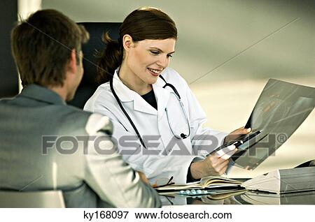 Stock Photo - Female doctor showing an X-Ray report to a patient. Fotosearch