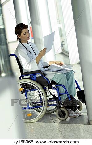 Female doctor sitting in a wheelchair and reading a medical record View Large Photo Image Stock Photo - Female doctor sitting in a wheelchair and reading a medical record. Fotosearch