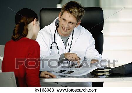 Stock Image - Male doctor explaining a medical record to a female patient. Fotosearch