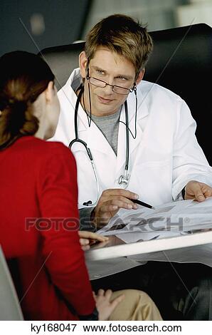 Stock Photo - Male doctor explaining a medical record to a female patient. Fotosearch