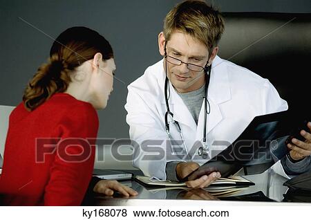 Male doctor showing an X-Ray report to a female patient View Large Photo Image Stock Photo - Male doctor showing an X-Ray report to a female patient. Fotosearch