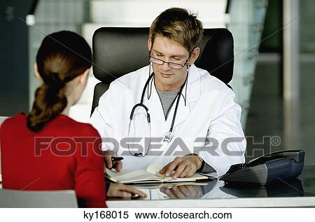 Male doctor sitting with a female patient and making notes in his office View Large Photo Image Stock Photography - Male doctor sitting with a female patient and making notes in his office. Fotosearch