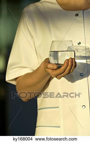 Mid section view of a young woman holding a glass of water View Large Photo Image Picture - Mid section view of a young woman holding a glass of water. Fotosearch