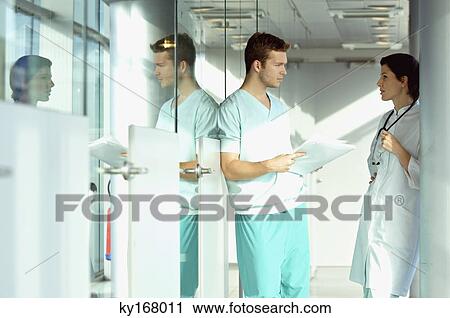 Stock Image - Side profile of two doctors discussing a medical record. Fotosearch