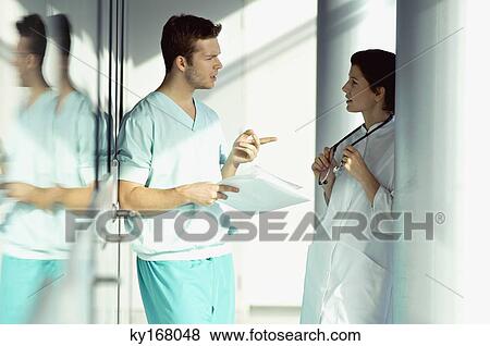 Stock Photo - Side profile of two doctors discussing a medical record. Fotosearch