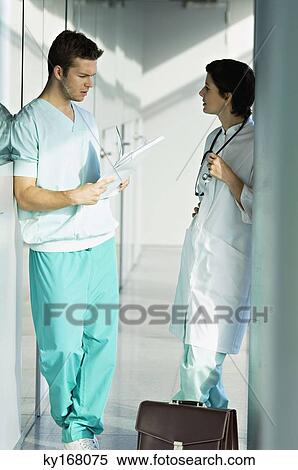 Stock Photography - Side profile of two doctors discussing a medical record. Fotosearch