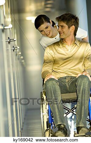Female doctor pushing a male patient sitting in a wheelchair View Large Photo Image Stock Image - Female doctor pushing a male patient sitting in a wheelchair. Fotosearch