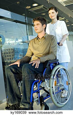 Female doctor pushing a male patient sitting in a wheelchair View Large Photo Image Stock Photo - Female doctor pushing a male patient sitting in a wheelchair. Fotosearch