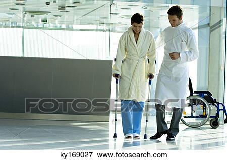 Male doctor assisting a female patient in walking on crutches View Large Photo Image Stock Photo - Male doctor assisting a female patient in walking on crutches. Fotosearch