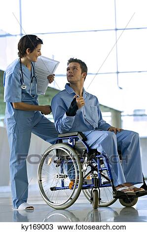 Male patient sitting in a wheelchair and looking at a female doctor standing behind him View Large Photo Image Stock Image - Male patient sitting in a wheelchair and looking at a female doctor standing behind him. Fotosearch