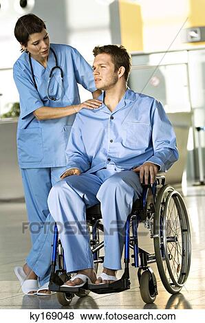 Male patient sitting in a wheelchair and a female doctor standing beside him View Large Photo Image Stock Photo - Male patient sitting in a wheelchair and a female doctor standing beside him. Fotosearch