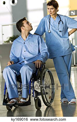 Male patient sitting in a wheelchair and looking at a female doctor standing beside him View Large Photo Image Stock Photograph - Male patient sitting in a wheelchair and looking at a female doctor standing beside him. Fotosearch