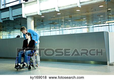 Mid adult man pushing a young woman sitting in a wheelchair View Large Photo Image Stock Photo - Mid adult man pushing a young woman sitting in a wheelchair. Fotosearch