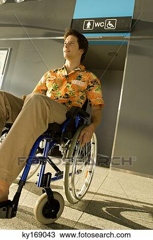 Mid adult man sitting in a wheelchair in front of a restroom entrance View Large Photo Image Stock Image - Mid adult man sitting in a wheelchair in front of a restroom entrance. Fotosearch