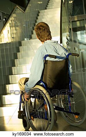 Rear view of a mid adult man sitting in a wheelchair and looking at a staircase View Large Photo Image Picture - Rear view of a mid adult man sitting in a wheelchair and looking at a staircase. Fotosearch