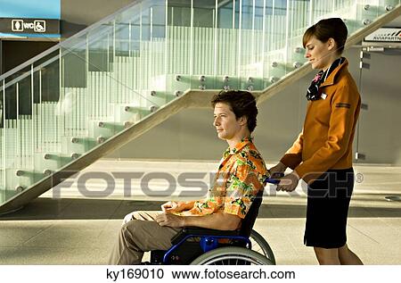 Side profile of a female cabin crew pushing a mid adult man sitting in a wheelchair View Large Photo Image Stock Image - Side profile of a female cabin crew pushing a mid adult man sitting in a wheelchair. Fotosearch
