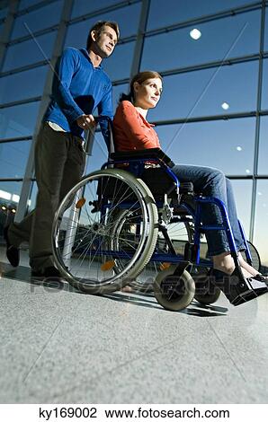 Side profile of a mid adult man pushing a young woman sitting in a wheelchair View Large Photo Image Stock Image - Side profile of a mid adult man pushing a young woman sitting in a wheelchair. Fotosearch