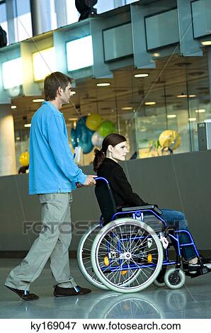Side profile of a mid adult man pushing a young woman sitting in a wheelchair View Large Photo Image Stock Photo - Side profile of a mid adult man pushing a young woman sitting in a wheelchair. Fotosearch