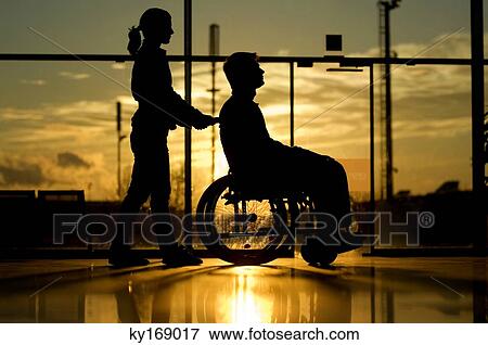 Silhouette of a woman pushing a male patient sitting in a wheelchair View Large Photo Image Stock Photo - Silhouette of a woman pushing a male patient sitting in a wheelchair. Fotosearch