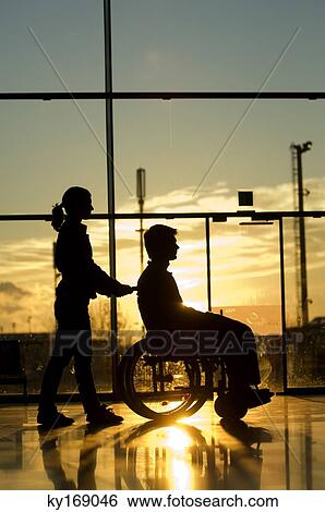 Silhouette of a woman pushing a male patient sitting in a wheelchair View Large Photo Image Stock Photograph - Silhouette of a woman pushing a male patient sitting in a wheelchair. Fotosearch