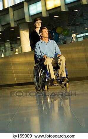 Young woman pushing a male patient sitting in a wheelchair View Large Photo Image Stock Photo - Young woman pushing a male patient sitting in a wheelchair. Fotosearch