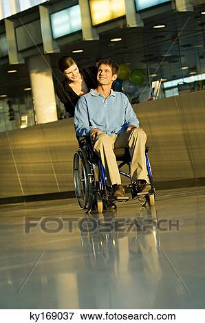 Young woman pushing a male patient sitting in a wheelchair View Large Photo Image Stock Photo - Young woman pushing a male patient sitting in a wheelchair. Fotosearch