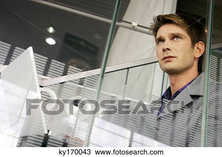 Businessman holding a laptop and looking away View Large Photo Image Stock Image - Businessman holding a laptop and looking away. Fotosearch