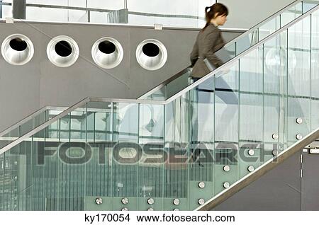 Picture - Businesswoman carrying a laptop and moving up on a staircase. Fotosearch