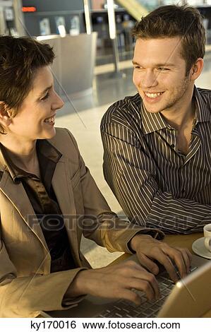 Businesswoman sitting with a businessman and smiling View Large Photo Image Stock Photograph - Businesswoman sitting with a businessman and smiling. Fotosearch