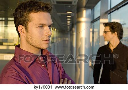 Close-up of a businessman with another businessman standing behind him View Large Photo Image Stock Image - Close-up of a businessman with another businessman standing behind him. Fotosearch