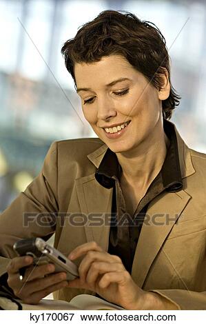 Close-up of a businesswoman operating a mobile phone and smiling View Large Photo Image Stock Photo - Close-up of a businesswoman operating a mobile phone and smiling. Fotosearch
