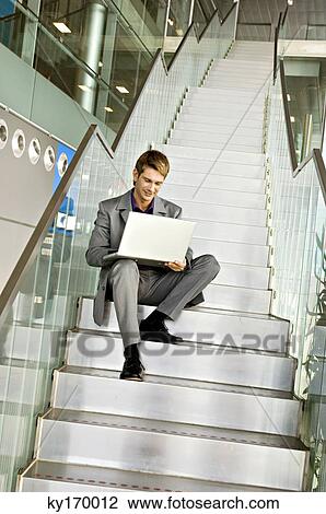 Low angle view of a businessman sitting on a staircase and using a laptop View Large Photo Image Stock Image - Low angle view of a businessman sitting on a staircase and using a laptop. Fotosearch