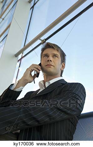 Low angle view of a businessman talking on a mobile phone View Large Photo Image Stock Photograph - Low angle view of a businessman talking on a mobile phone. Fotosearch
