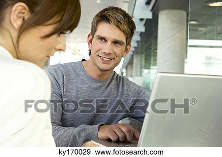 Mid adult man talking with a young woman and smiling View Large Photo Image Stock Photo - Mid adult man talking with a young woman and smiling. Fotosearch