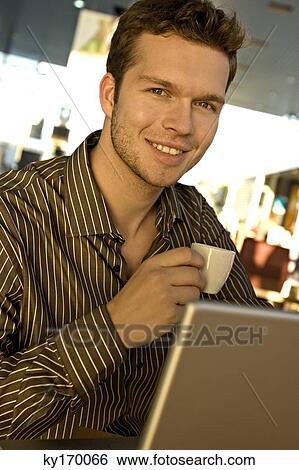 Portrait of a businessman holding a tea cup in front of a laptop View Large Photo Image Stock Photograph - Portrait of a businessman holding a tea cup in front of a laptop. Fotosearch